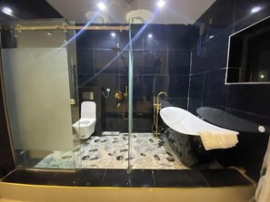 A modern bathroom with a glass-enclosed shower, a white toilet, and a black bathtub. - Royal Swiss Apartments and Suites (Enugu)