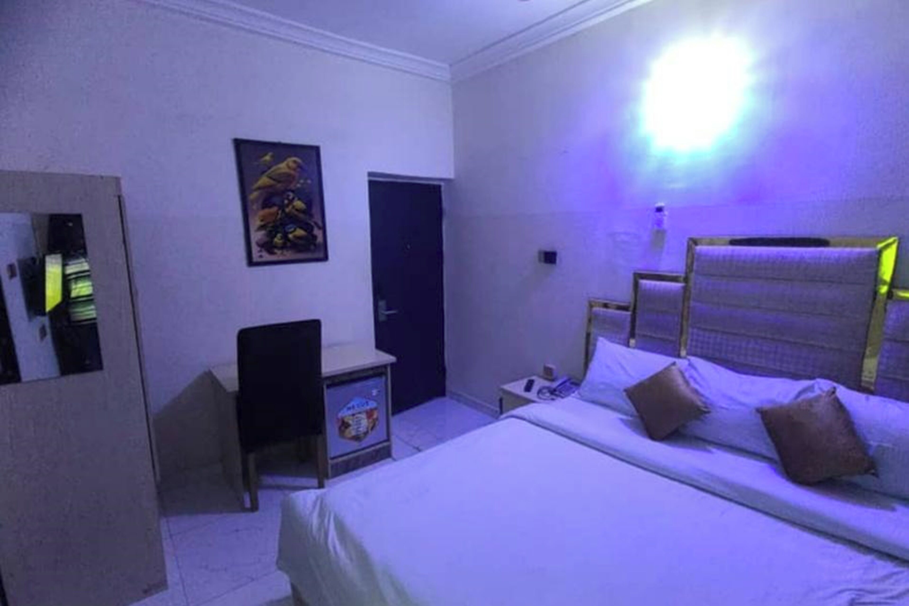 A bedroom with a bed, a desk, a chair, and a door.