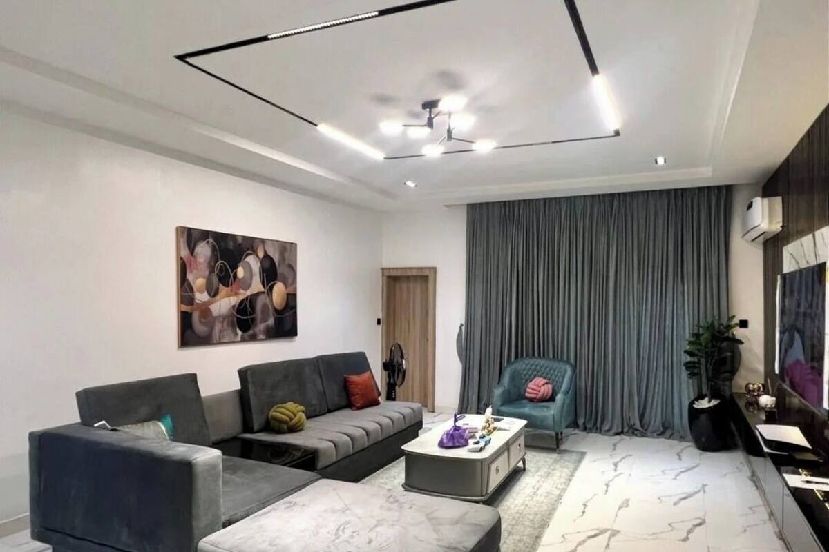 Una sala moderna con un sofá seccional, una chaise lounge, una mesa de centro y un cuadro grande en la pared.