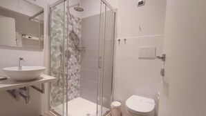 Une salle de bain moderne avec une douche à parois de verre, un lavabo blanc et des toilettes.