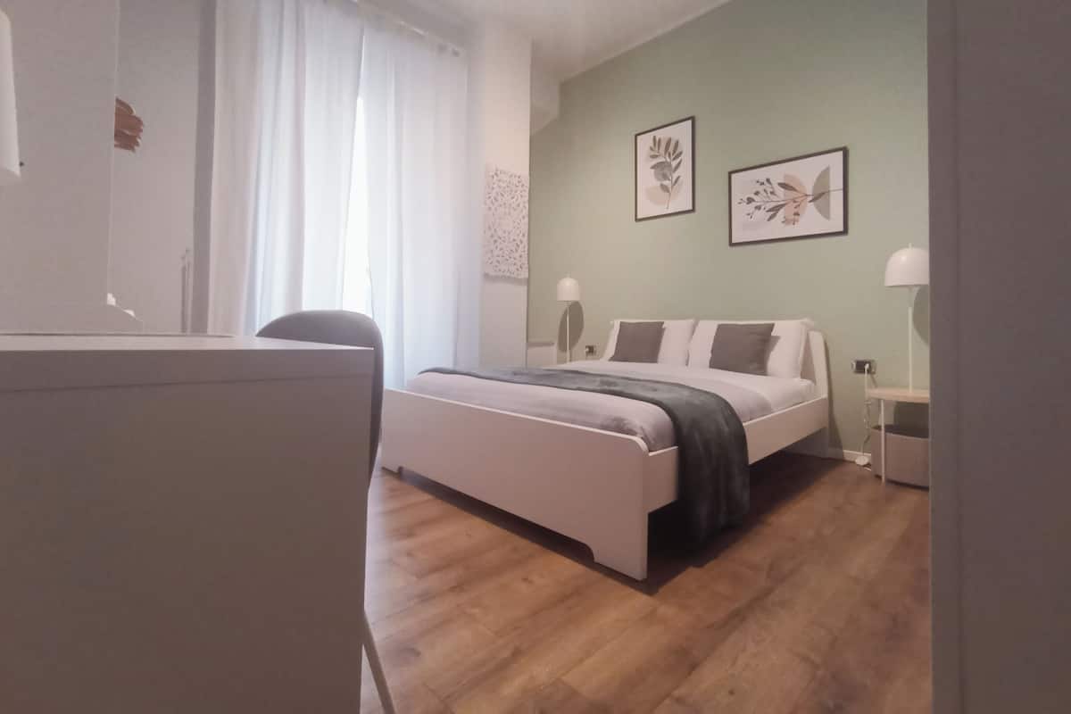 A bedroom with a bed, bedside tables, a desk, and a chair.