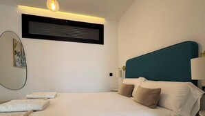 Una camera da letto moderna con un letto, lampade da comodino, un condizionatore d'aria a parete e un lampadario.