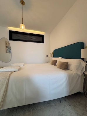 A modern bedroom with a bed, bedside lamps, a wall-mounted air conditioning unit, and a ceiling light fixture. - Malvasia 1 Bedroom by Hello Homes Sitges (Sitges)