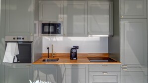 Una cucina con mobili grigi, un forno in acciaio inossidabile, un forno a microonde e una macchina da caffè sul piano di lavoro.