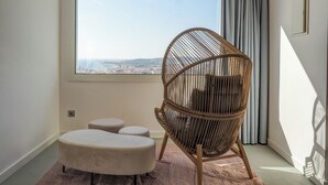 A room with a large window, a wicker chair, and two ottomans on a pink rug. - Pink Suite by Hello Homes Sitges (Sitges)