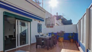 A patio with a dining table and chairs, a sliding glass door, and potted plants. - Central Terrace by Hello Homes Sitges (Sitges)