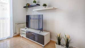 A modern living room with a flat-screen TV on a white entertainment unit, a radiator, and a potted plant. - Ribes Duplex by Hello Homes Sitges (Sitges)