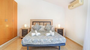 A bedroom with a bed, nightstands, a wardrobe, and an air conditioning unit. - Ribes Duplex by Hello Homes Sitges (Sitges)