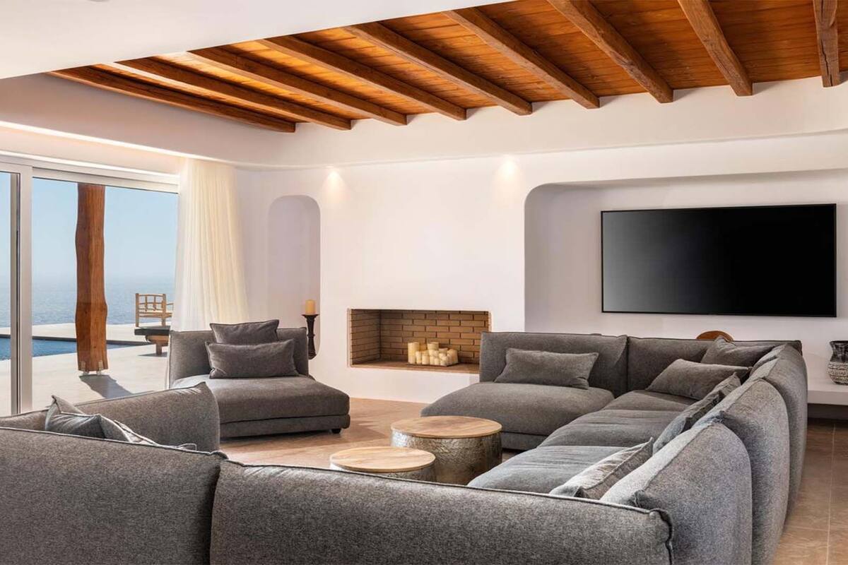 A modern living room with a large sectional sofa, a flat-screen TV, and a fireplace.
