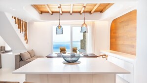 Uma sala de jantar moderna com uma ilha grande, cadeiras de madeira e luminárias pendentes.