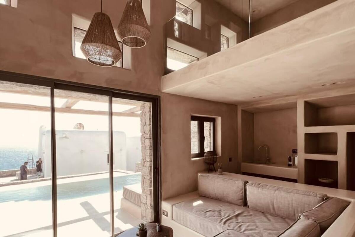 A modern living room with a large sectional sofa, a small round table, and a view of a pool and ocean.