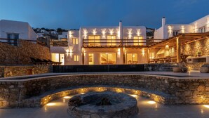Uma villa moderna com um pátio de pedra, área de estar ao ar livre e lareira.