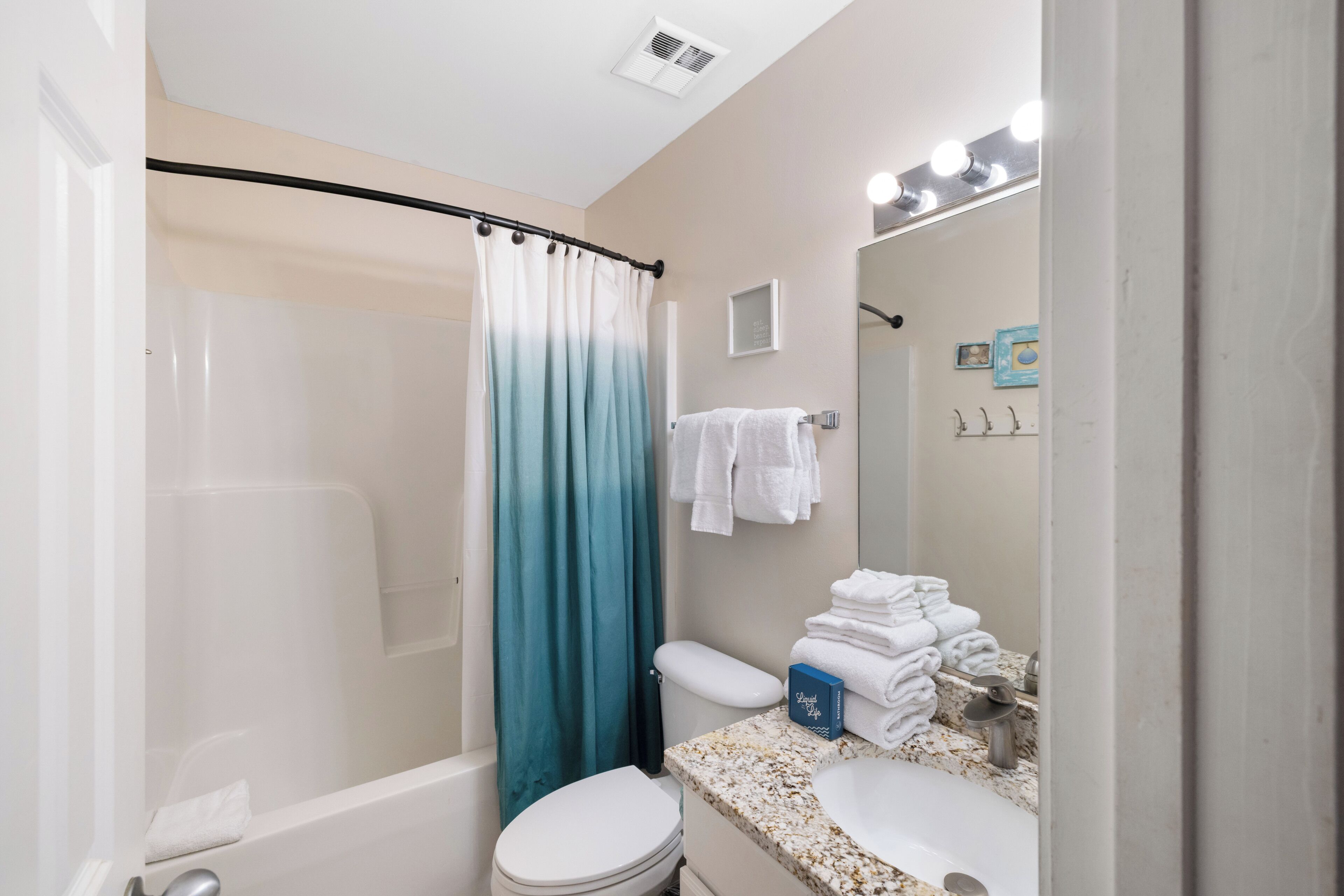 Une salle de bain équipée d’une douche, de toilettes, d’un lavabo et d’un miroir avec éclairage.