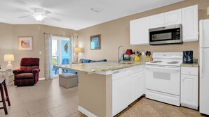Una cocina moderna con armarios blancos, microondas integrado y estufa.