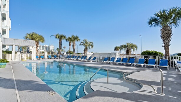 Una piscina con sillas azules y palmeras.