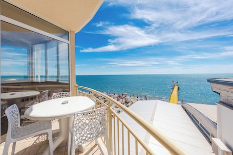 A balcony with a view of the sea, white outdoor furniture, and a yellow lifebuoy.