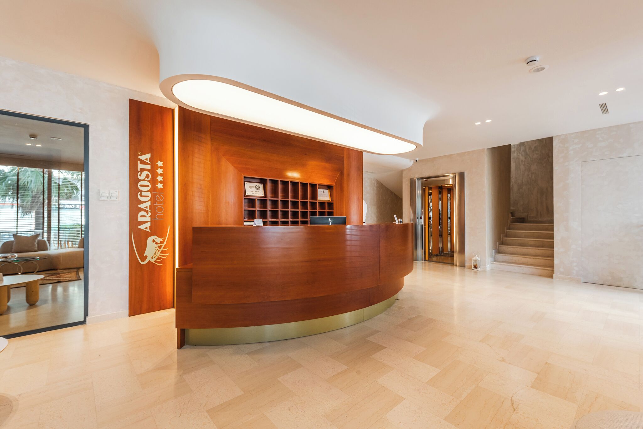 A reception desk with a wooden finish and a modern light fixture above it.