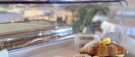A display case with pastries, including croissants and a sign indicating 'CREAM CRUST'.