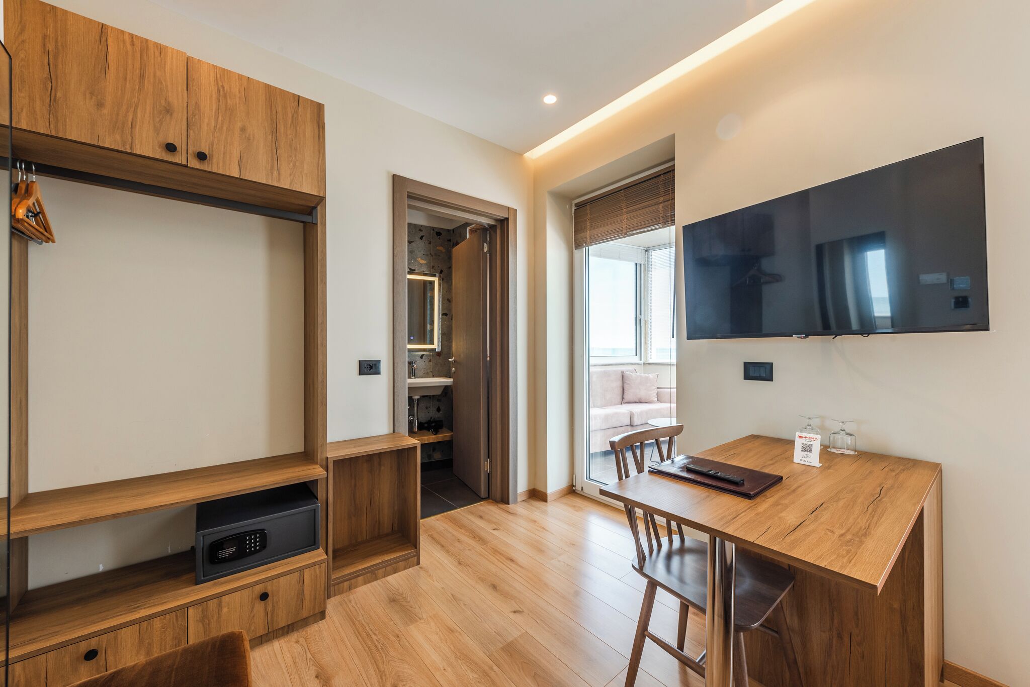 Une cuisine moderne avec des meubles en bois, un micro-ondes encastré et un coin repas comprenant une table et des chaises en bois.