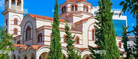 A historic church with multiple domes and bell towers, surrounded by tall trees.