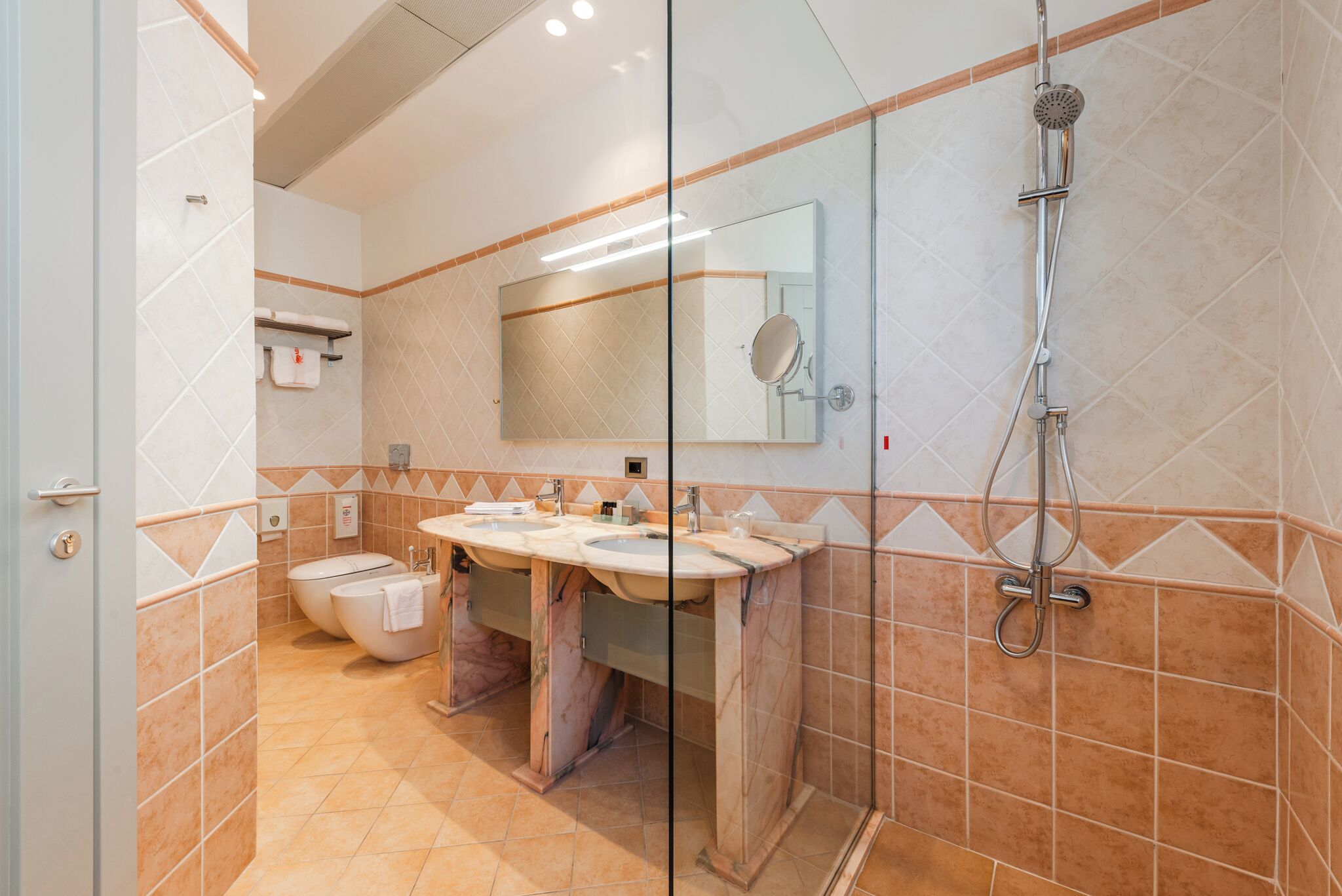 Une salle de bain avec deux lavabos, des toilettes et une douche.