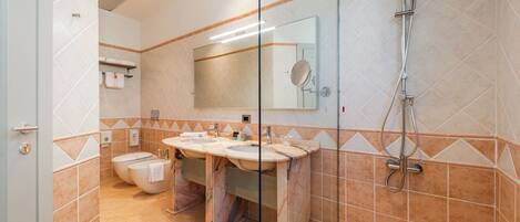 A bathroom with two sinks, a toilet, and a shower.