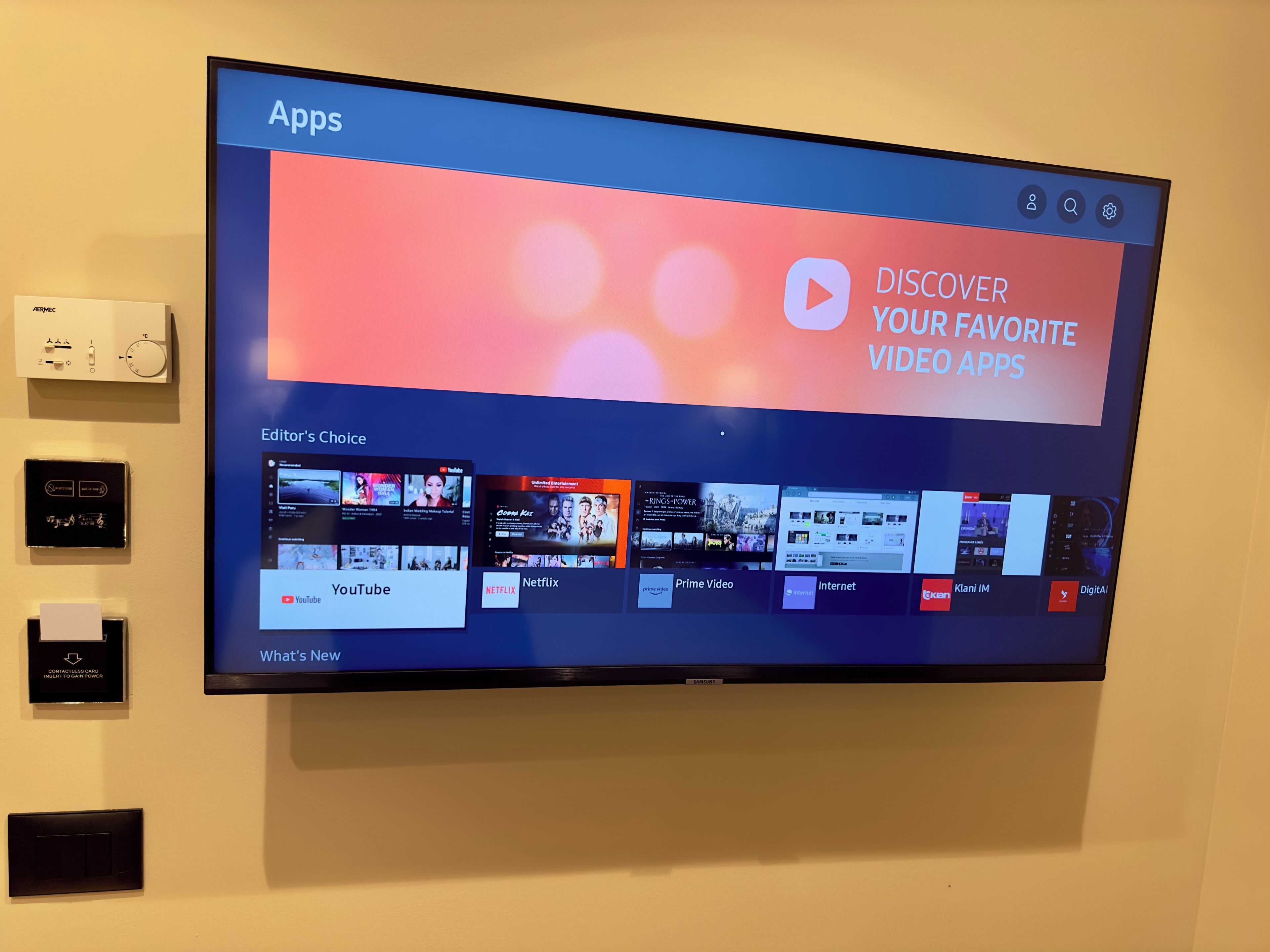 A flat-screen TV mounted on a wall displaying a video streaming app interface with multiple video app icons.
