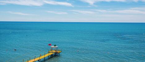 A pier extending into a calm sea with clear skies.