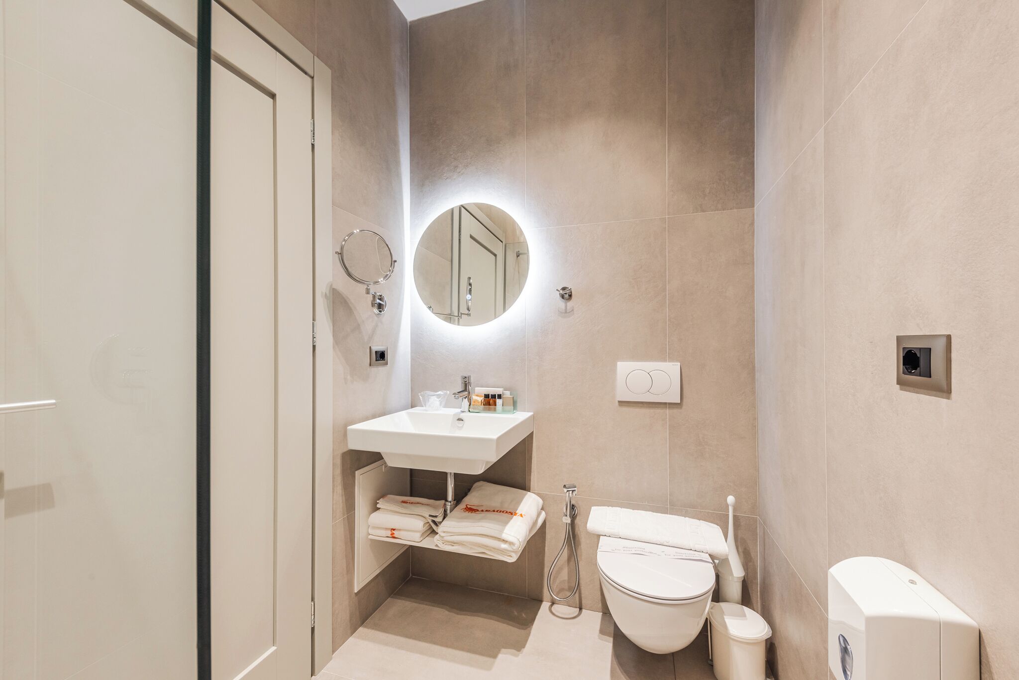 Ein modernes Badezimmer mit Toilette, Waschbecken und Spiegel.