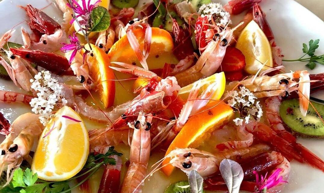 Plato de mariscos con camarones, rodajas de limón y hierbas.