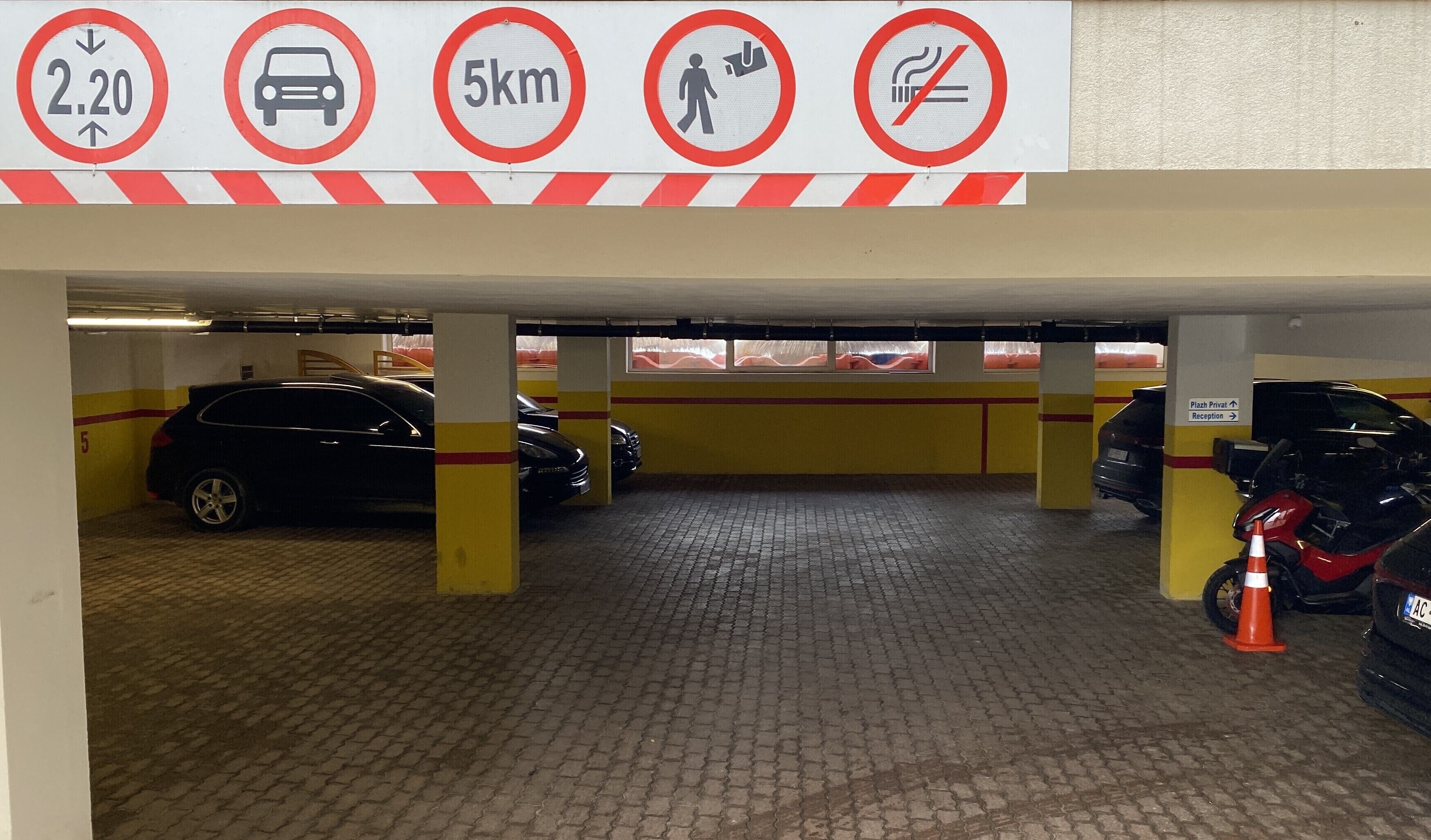 A parking garage with a speed limit sign of 2.20, a 5km limit, a no pedestrian crossing, and a no smoking sign.