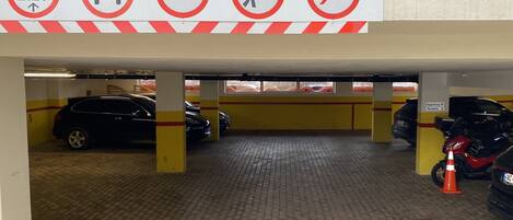A parking garage with a speed limit sign of 2.20, a 5km limit, a no pedestrian crossing, and a no smoking sign.