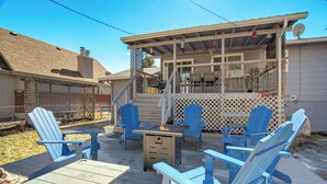 Una terraza al aire libre con sillas Adirondack azules, un brasero y un patio cubierto.