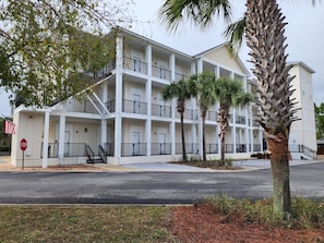 A multi-story hotel with balconies, palm trees, and a stop sign.