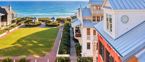 A coastal property with a view of the ocean, a paved pathway, and a well-maintained lawn.