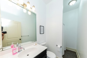 Een badkamer met een grote spiegel, een witte wastafel en een toilet.