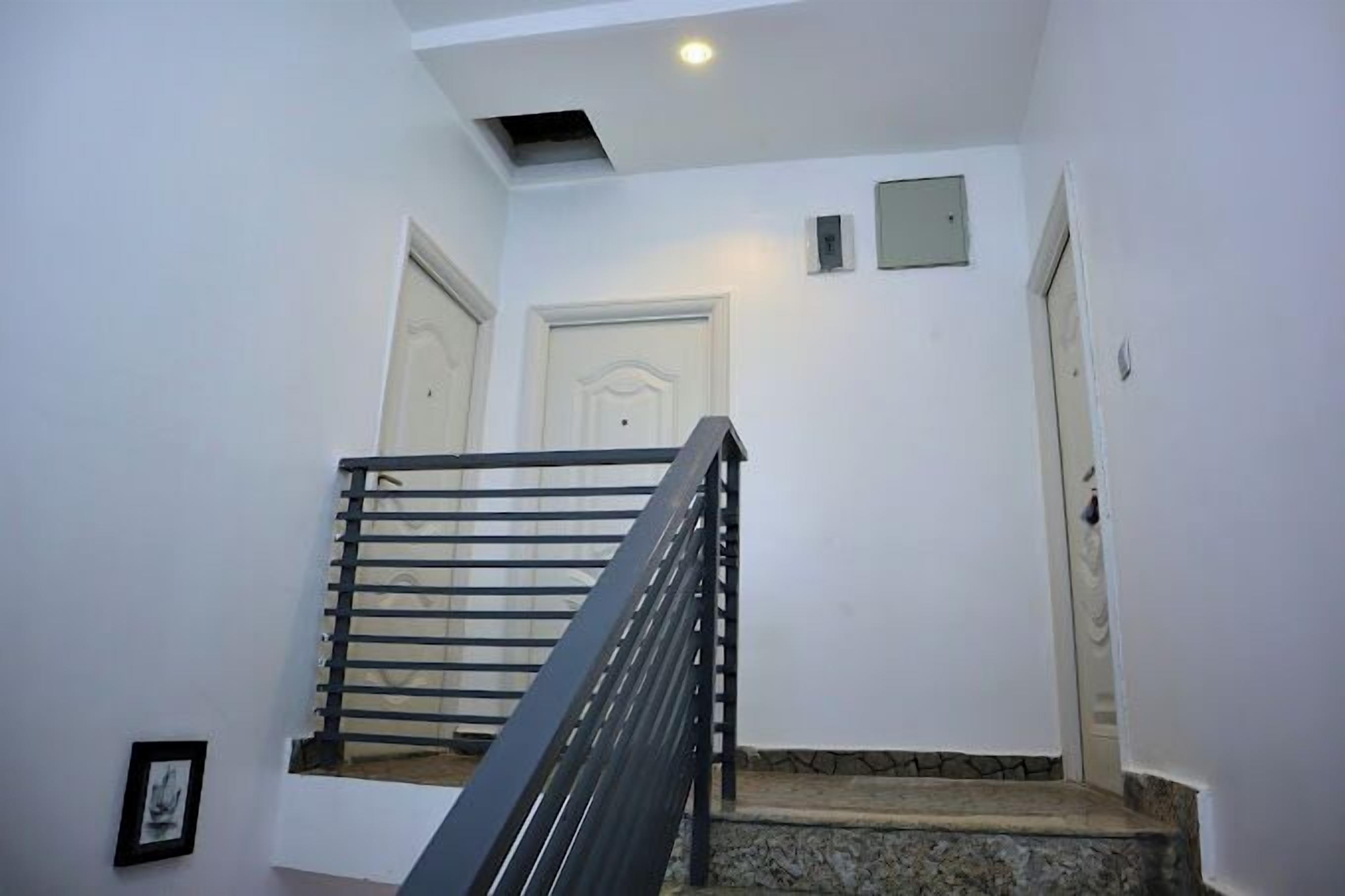 Eine Treppe mit Metallgeländer führt zu einer Zwischenebene mit zwei Türen.