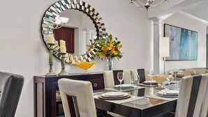 A modern dining area with a round table, chairs, and a decorative mirror. - Legacy Tower II 305 | Stunning Coastal Views! (Gulfport)