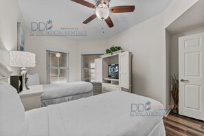 Um quarto moderno com duas camas, um ventilador de teto, uma TV e um guarda-roupa branco.