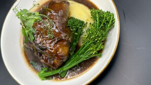 Une assiette contenant un plat de viande, des brocolis et un accompagnement crémeux.