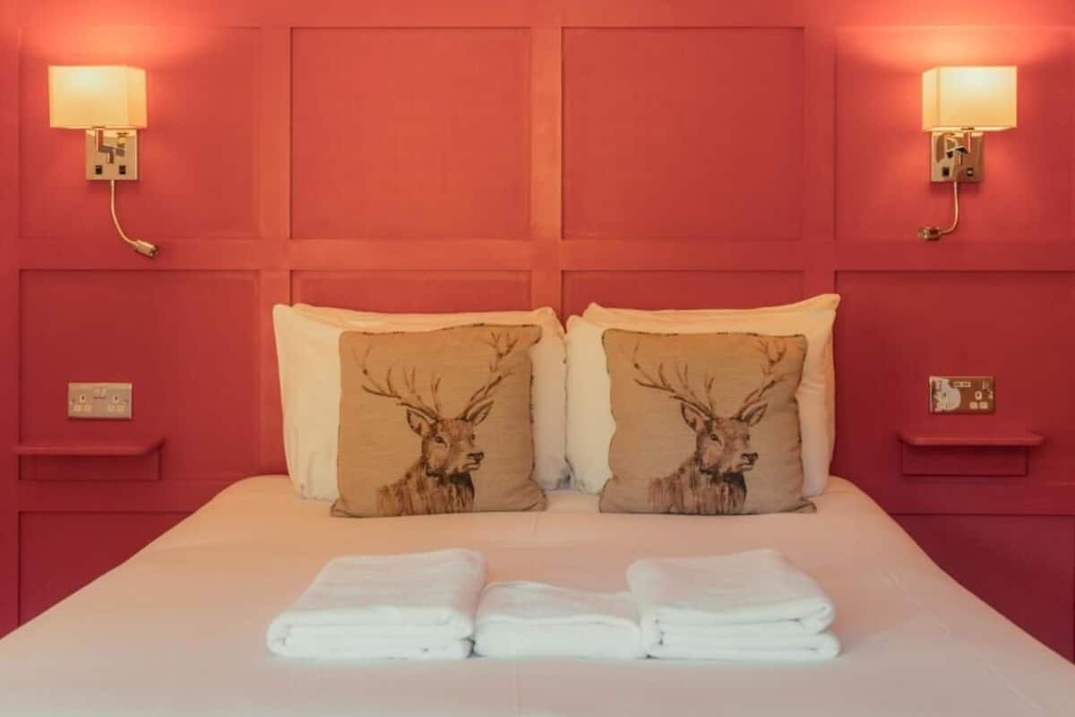A hotel room with a large bed, two wall-mounted lamps, and two nightstands.