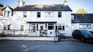 Un bâtiment blanc avec une enseigne indiquant « The Ballinturgh Inn » et une voiture noire garée devant.