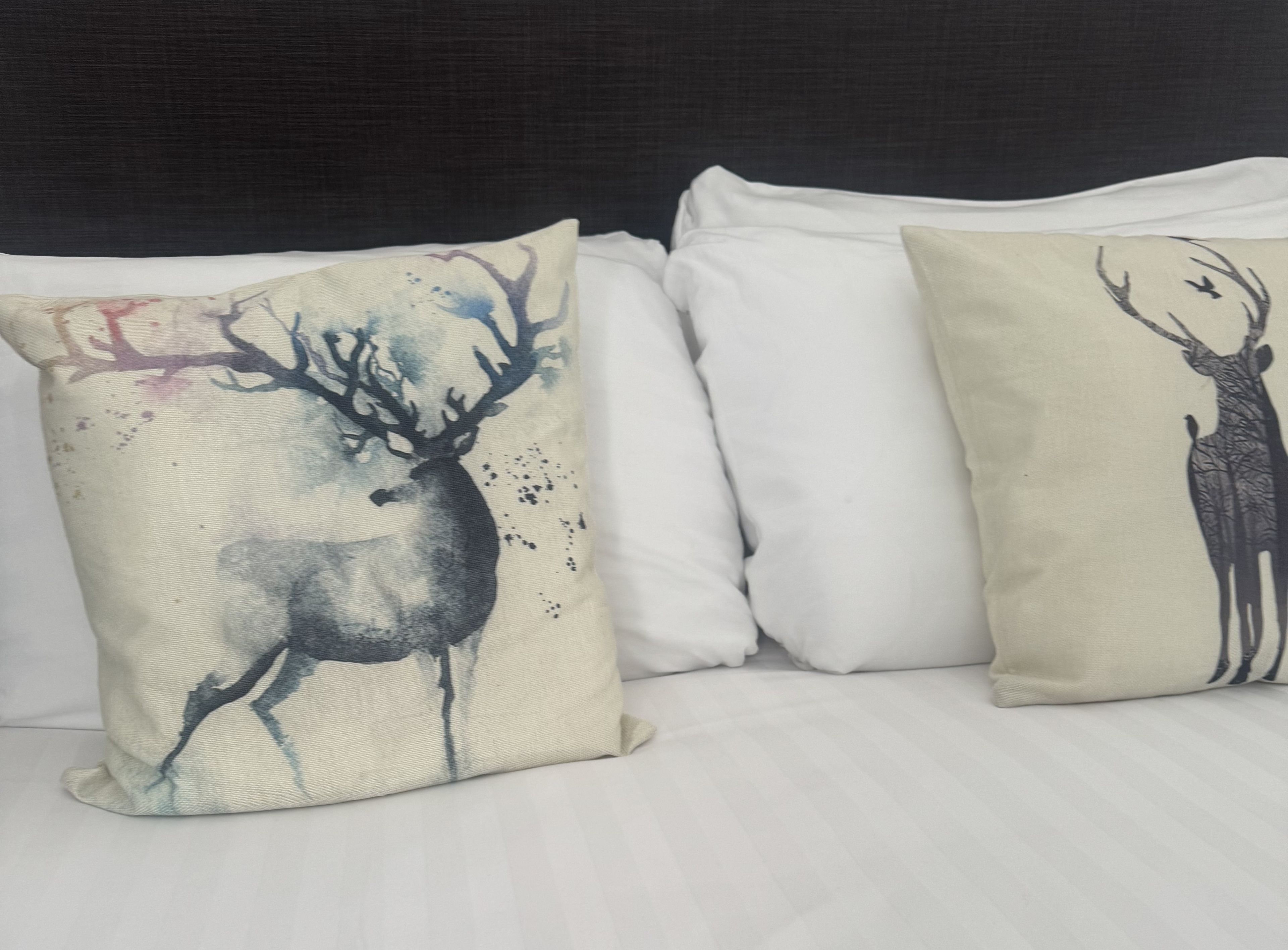 Dois travesseiros com estampas de veados na cama.