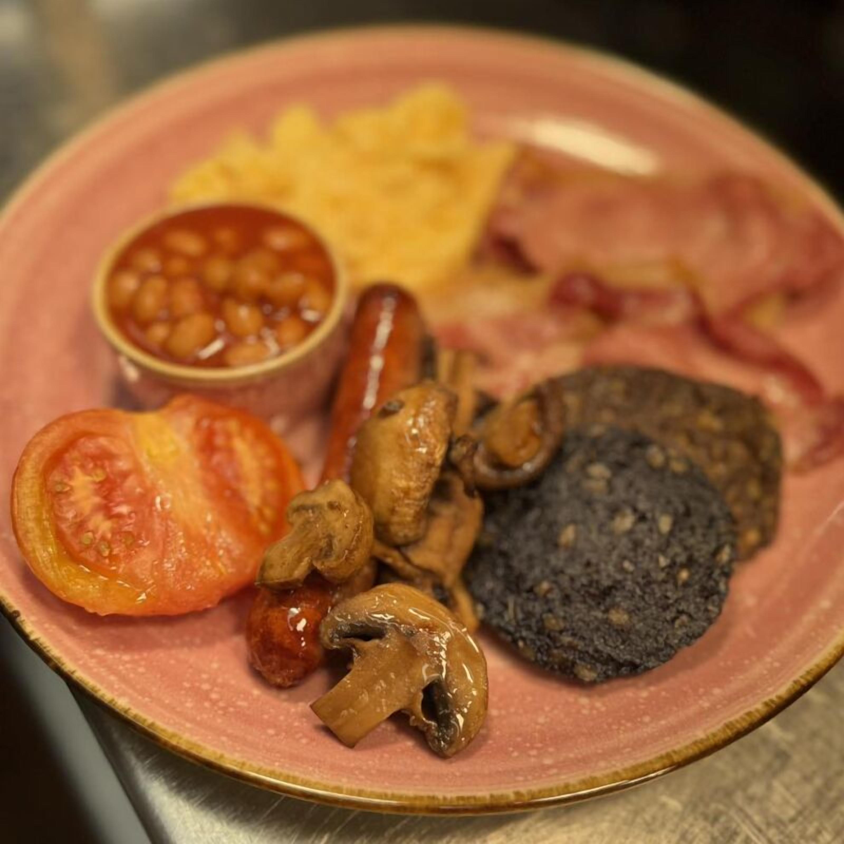A plate with beans, sausage, tomato, mushrooms, black pudding, and hash browns.