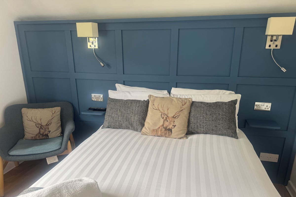 A bedroom with a bed, pillows, a chair, and bedside tables.