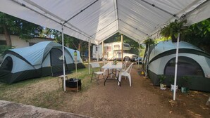 A camping area with multiple tents, a table, and chairs under a large canopy. - 212A-HOUSE TENT & GET 60-10 = 50 BIOBAY TOUR TEXT 787 614-5678 DATE-NAMES-EMAIL (Esperanza)