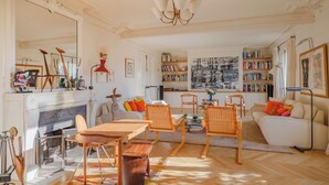 Ein geräumiges Wohnzimmer mit Kamin, Bücherregalen und einem großen Gemälde.