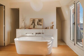 A modern bathroom with a freestanding bathtub, a large window, and a minimalist design. - Paris St Germain Loft Residence (Paris)