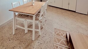 Uma cozinha espaçosa com armários brancos, uma mesa de jantar de madeira e uma janela que proporciona iluminação natural.
