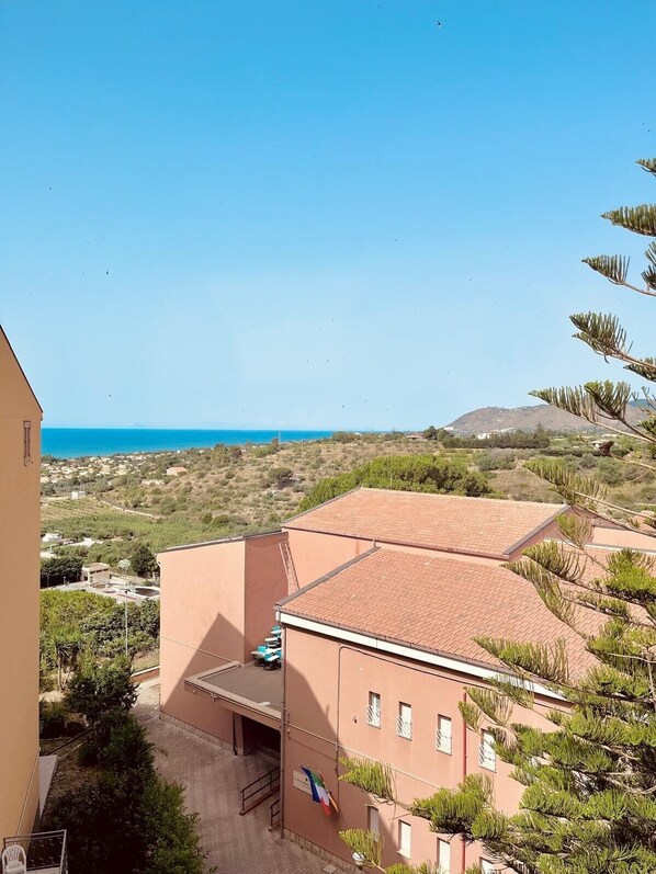 A building with a red-tiled roof, a flag, and a view of the sea.